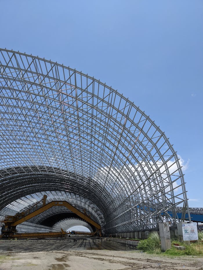 about-us-02 Large steel frame structure under a clear blue sky in Bangladesh, showcasing modern engineering.