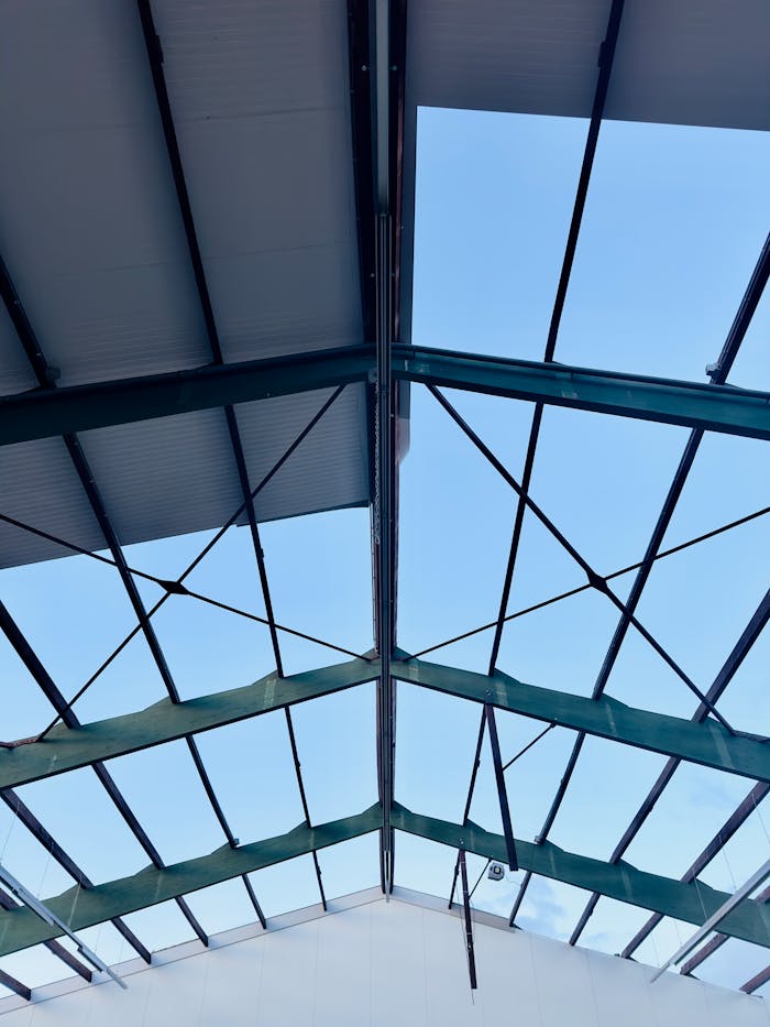Looking up at a modern steel roof frame with blue sky background.